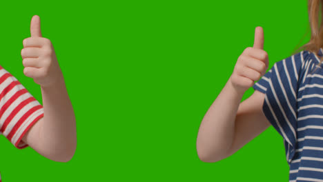 Close-Up-Of-Two-Young-Children-Giving-Thumbs-Up-Gesture-To-Camera-Against-Green-Screen